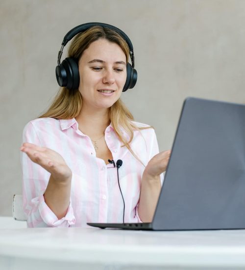 Engaged in distant training. Active young woman remote worker take part in virtual meeting using home computer. Female student participate in video conference wearing headset.